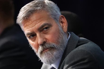 George Clooney alaposan ellenőrzi a kezébe adott fegyvereket mielőtt elindul a felvétel