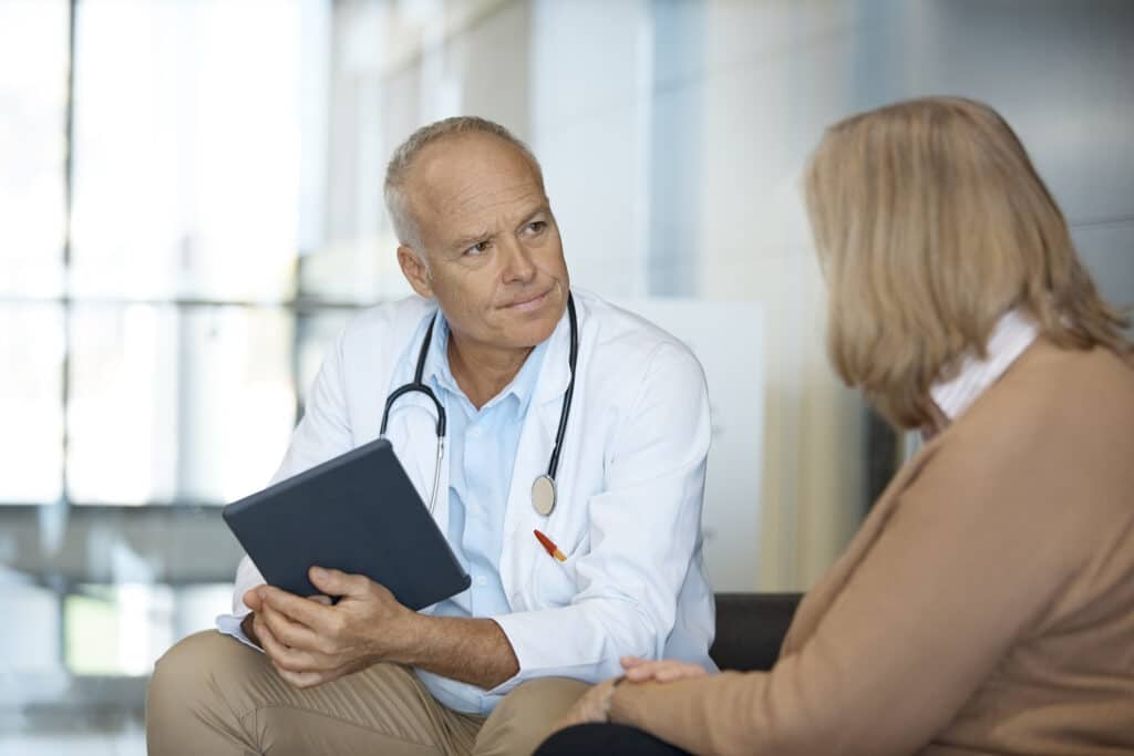 Doctor With Digital Tablet Looking At Woman