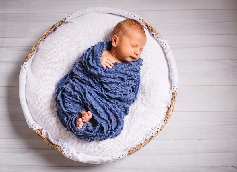 newborn-baby-enveloped-blue-scarf-sleeps-white-pillow_8353-848